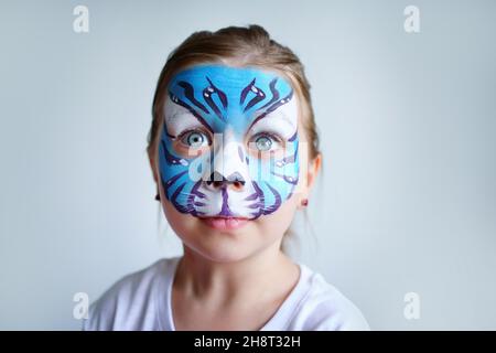 Mädchen Aqua Make-up in Form eines blauen Wassertiger Tierkreises auf weißem Hintergrund, Konzeptsymbol des neuen Jahres 2022, überraschte Porträt Stockfoto