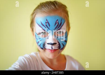 Mädchen Aqua Make-up in Form eines blauen Wassertiger Tierkreises auf gelbem Hintergrund, Konzeptsymbol des neuen Jahres 2022, Lächeln Porträt Stockfoto