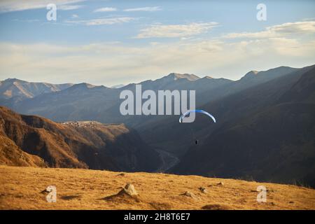 Gleitschirm Silhouette fliegen über Hügel Kaukasus Berge an einem sonnigen Tag. Beauty-Welt. Svanetien, Georgien, Europa Stockfoto