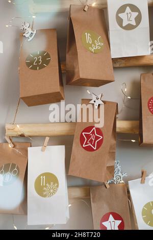 Hängender Weihnachtsadventkalender an der Wand. Handgefertigte Basteltaschen mit Geschenken und Aufgaben für Kinder. Countdown für Heiligabend, warten auf Wunder Stockfoto