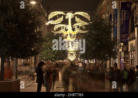 Dublin, Irland - 13. November 2021: Wunderschöne Aussicht auf festliche Weihnachtsbeleuchtungen in der geschäftigen Henry Street während der COVID-19-Pandemie. Nachtleben Stockfoto