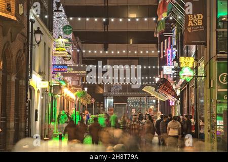 Dublin, Irland - 13. November 2021: Wunderschöne Aussicht auf das Nachtleben in der Crown Alley Street mit festlicher Dekoration für Weihnachten am Abend Stockfoto