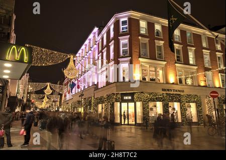 Dublin, Irland - 13. November 2021: Wunderschöne Aussicht auf das Brown Thomas Hotel am Abend, dekoriert mit Weihnachtslichtern auf der überfüllten Grafton Street Stockfoto