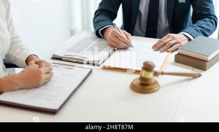 Rechtskonzept der Jurist, der ein offizielles Dokument liest, das sein Berater, der Mann in weißem langärmeligen Hemdhand an ihn hält und das Zeichen schreibt Stockfoto