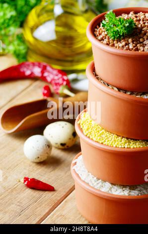 Getreidekörner in Keramikschüsseln auf Holztisch Stockfoto