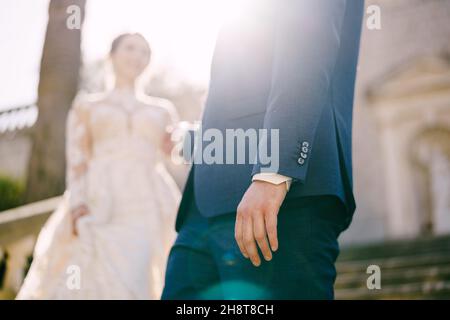 Der Bräutigam gibt der Braut die Hand, die die Steintreppe hinuntergeht. Weichzeichnen Stockfoto