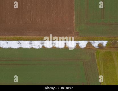 Unentschlossene Natur im Übergang zwischen Winter und Herbst. Ein Feld von oben mit Farben und Teilen von weißem Schnee. Stockfoto