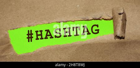 Das Wort Hashtag erscheint hinter zerrissenem Papier. Stockfoto