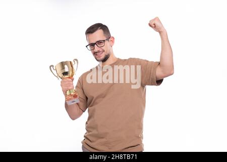 Mann sehr glücklich und aufgeregt, die Waffen heben, feiern einen Sieg oder Erfolg Holding Trophy. Sieger Zeichen. Eine isolierte mit Trophäe in den Händen Stockfoto