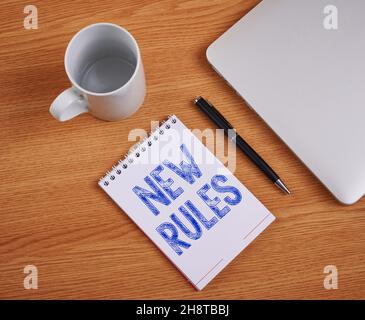 Konzeptionelle Anzeige Neue Regeln. Wort für vor kurzem eine einer Reihe von expliziten oder verstandenen Vorschriften geschlossen Laptop neben leerem Journal mit Stift und Stockfoto