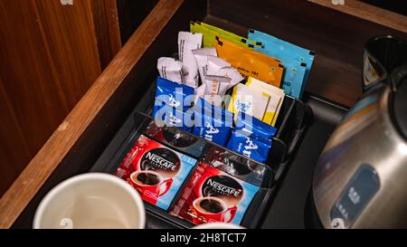 Selektive Konzentration von Milchpulver, Zucker und Kaffeepaketen an der Minibar-Theke. Stockfoto
