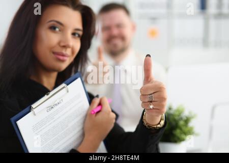 Schöne Frau hält einen Vertrag und zeigt ok Geste Stockfoto
