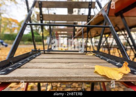 Kopenhagen, Dänemark - 31. Oktober 2021: Unterseite des Stuhls, gedreht um vor dem Ende der Saison, mit gefallenes orangefarbenes Blatt im Vordergrund, Stockfoto