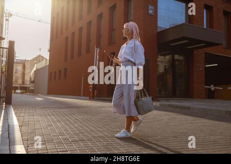 Junge Frau, die auf der Straße steht und Mobiltelefon hält Stockfoto