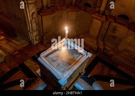 Brennende Kerze auf dem Stein des Engels, vermutlich ein Fragment des großen kreisförmigen Steins, der das Grab Jesu in der Engelskapelle versiegelte, Der erste Raum in der Edicule oder Anastasia-Rotunde, der das Grab Jesu Christi in der Grabeskirche in der Altstadt des Christlichen Viertels, Ostjerusalem Israel, einschließt Stockfoto