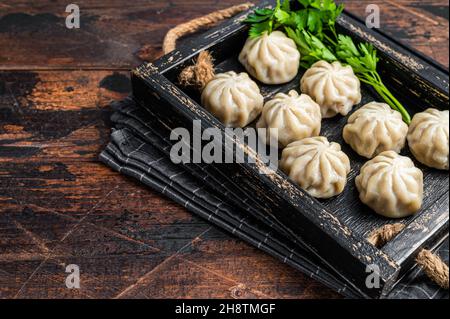 Momo Knödel in einem Holztablett mit Kräutern. Dunkler Holzhintergrund. Draufsicht. Speicherplatz kopieren Stockfoto