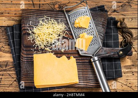 Geriebener Cheddar-Käse auf einem Holzbrett. Holzhintergrund. Draufsicht Stockfoto