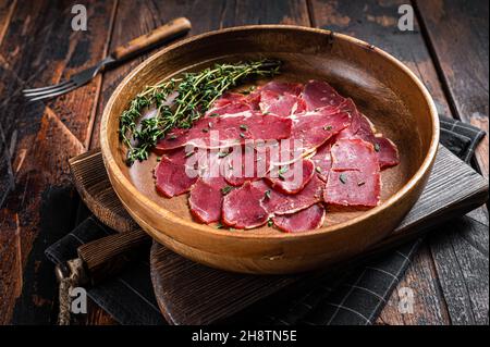 Pastrami-Scheiben, getrocknetes Rinderfleisch mit Kräutern in Holzplatte. Holzhintergrund. Draufsicht Stockfoto