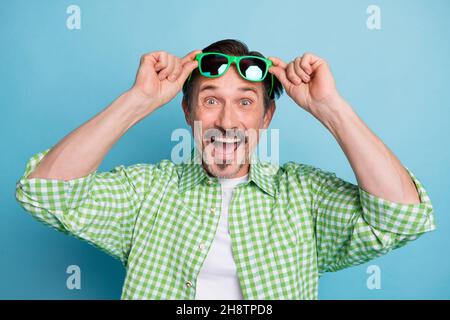 Portrait von attraktiven fröhlich verrückt funky Mann berühren Specs große Nachrichten Reaktion isoliert über hellen blauen Hintergrund Stockfoto