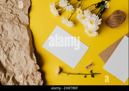 Leere Karte mit Umschlag und Blume ist auf gelbem Hintergrund platziert Stockfoto