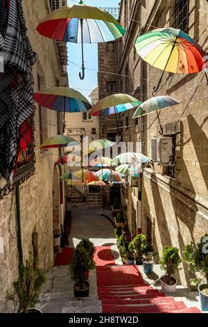 MARDIN, TÜRKEI - 10. OKTOBER 2020: Dies ist eine alte Straße, die mit bunten Sonnenschirmen im historischen Zentrum der Stadt geschmückt ist. Stockfoto