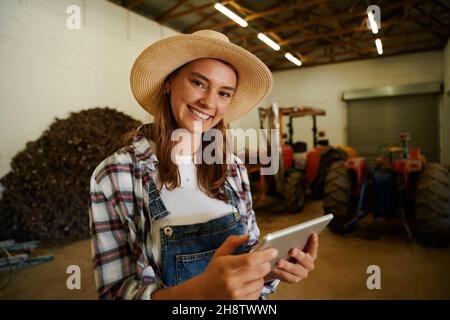 kaukasische Bäuerin lächelt, während sie das digitale Tablet hält Stockfoto