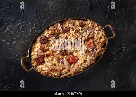 Risotto ai funghi, Pilzrisotto, rustikaler Reis mit Pilzen, Spitzenaufnahme auf schwarzem Hintergrund Stockfoto