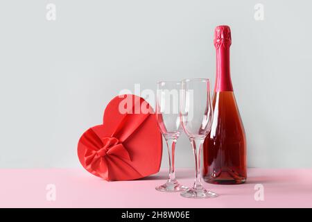 Valentinstag Komposition aus Champagner oder Sekt, Herz-Geschenkbox, Weingläser auf blauem Hintergrund. Grußkarte mit Kopierplatz. Stockfoto