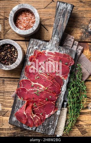 Getrocknete Pastrami-Scheiben, Rinderfleisch mit Kräutern auf Holzbrett. Holzhintergrund. Draufsicht Stockfoto