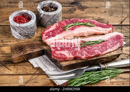 Prime Black Angus Beef Steaks Raw Striploin oder New York. Holzhintergrund. Draufsicht Stockfoto