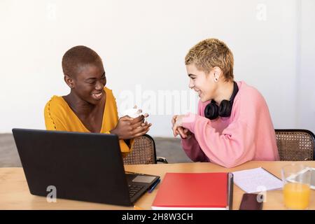 Frauen mit einem multiethnischen Lächeln, die im Heimbüro einen Laptop benutzen Stockfoto