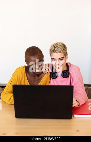 Eine lächelnde Frau, die im Büro einen Laptop benutzt Stockfoto