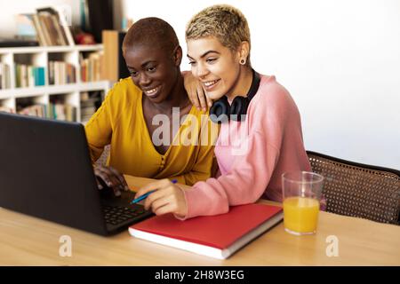 Eine lächelnde Frau, die im Büro einen Laptop benutzt Stockfoto