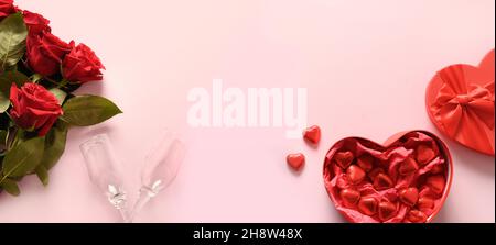 Valentinstag-Banner mit roten Schokoladenbonbons, Strauß roter Rosen und Weingläsern auf rosa Hintergrund. Grußkarte mit Kopierplatz. Stockfoto