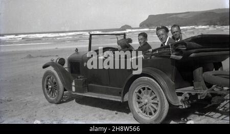 1920s, historisch, draußen an einem Sandstrand, parkte ein oben offener Wagen der Ära, in dem Fahrer und Passagiere saßen, die Seeluft und den Blick auf das Meer genossen, Devon, England, Großbritannien. Ein Benzin oder Kraftstoff kann an der Plattform unter der Beifahrertür des Fahrzeugs mit der Aufschrift „Shell Motor Spirit“ befestigt werden. Der Begriff Motorenbrand war der Name, der in Großbritannien vom Ende des 19th. Jahrhunderts bis zum 1930s weitgehend für Benzin verwendet wurde. Stockfoto