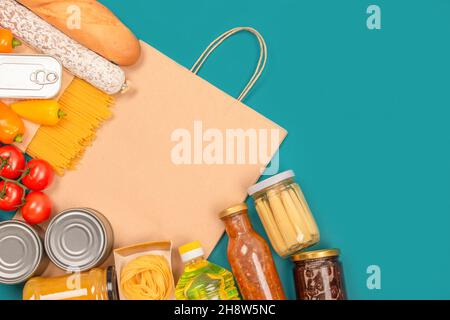 Food Bank, Food Delivery Konzept. Lebensmittelspenden und Papiertüte auf grünem Hintergrund mit Platz für Kopien - Pasta, frisches Gemüse, Konserven, Baguette Stockfoto