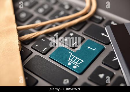 Internet-Shopping-Konzept mit Nahaufnahme der Tastatur mit eingezogenem Warenkorb in der Taste Kreditkarte und Einkaufstasche eingeben. Erhöhte Ansicht. Stockfoto