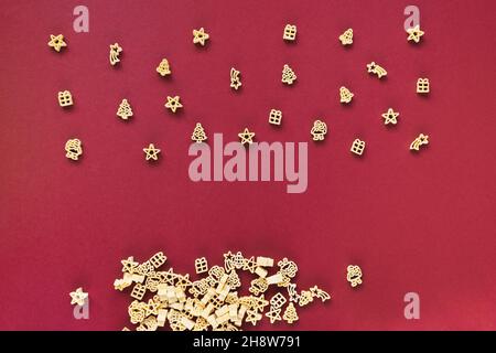 Rohe weihnachtliche Pasta auf rotem Hintergrund. Kochen festliches Weihnachtsessen für Kinder und Familienkonzept. Kopiespeicherplatz in der Draufsicht Stockfoto