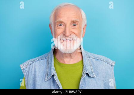 Foto von lustig beeindruckt Rentner tragen Vintage Jeans Weste lächelnd isoliert blauen Hintergrund Stockfoto