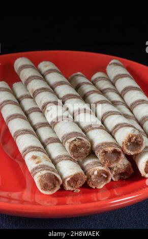 Die Sweet Sticks mit Füllung in roter Platte auf schwarzem Hintergrund. Dessert bis Tee auf schwarzem Hintergrund Stockfoto