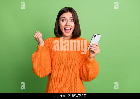 Portrait von attraktiven trendigen fröhlichen Mädchen mit Gerät Freude Feedback folgen isoliert über helle grüne Farbe Hintergrund Stockfoto