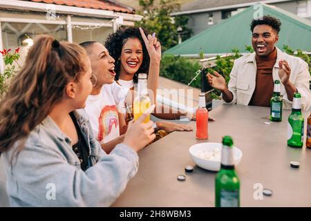 Kalte Biere und eine gute Zeit. Eine Gruppe glücklicher junger Menschen, die zusammen lachen, während sie auf dem Dach rumhängen. Fröhliche Freunde genießen alkoholische d Stockfoto