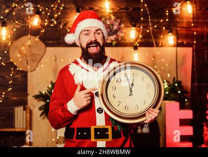 Warten auf Wunder. Winterferien. Warten Sie auf Weihnachtsgeschenke. weihnachtsmann halten Uhr. Winterzeit. Frohe Weihnachten. Mann weihnachtsmann Hut. Neujahr Mitternacht. Zeit Stockfoto