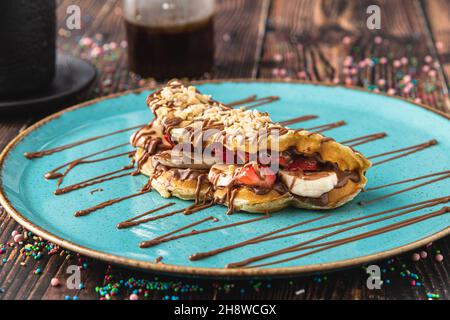 Sandwich-Waffeln mit Banane, Erdbeere und Schokolade und Pistazie auf der Oberseite Stockfoto