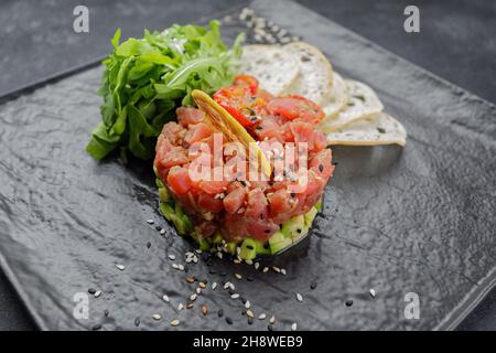 Lachs-Tartar mit Avocado auf schwarzem Hintergrund Stockfoto