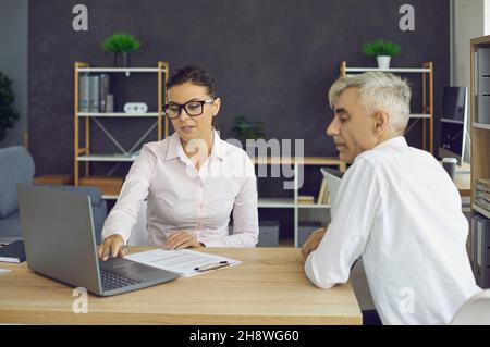 Junge Mitarbeiterin diskutiert E-Mails mit der leitenden Führungskraft am Arbeitsplatz Stockfoto