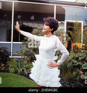 Die deutsche Schauspielerin Uschi Glas als Sängerin barfuß im Garten vor der TV Sendung 'Musik aus Studio B', Deutschland 1960er Jahre. Die deutsche Schauspielerin Uschi Glas als Sängerin vor der Fernsehsendung 'Musik aus Studio B', Deutschland 1960s. Stockfoto