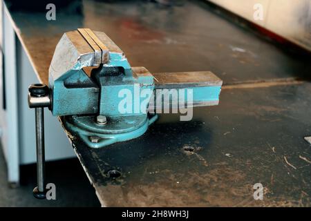 Metall-Werkbank mit Viskel zum Spannen von Teilen. Blick auf den Arbeitsplatz in der Werkstatt. Ordnung und Sauberkeit am Arbeitsplatz. Arbeitsschutz. Hintergrund Stockfoto