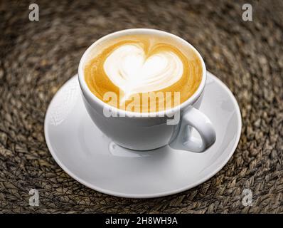 Tasse Kaffee mit herzförmiger Form auf grünem Hintergrund Stockfoto