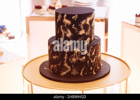 Leckere zweistufige Schokoladenkuchen zum Geburtstag mit goldenen Verzierungen. Schokoriegel. Stockfoto